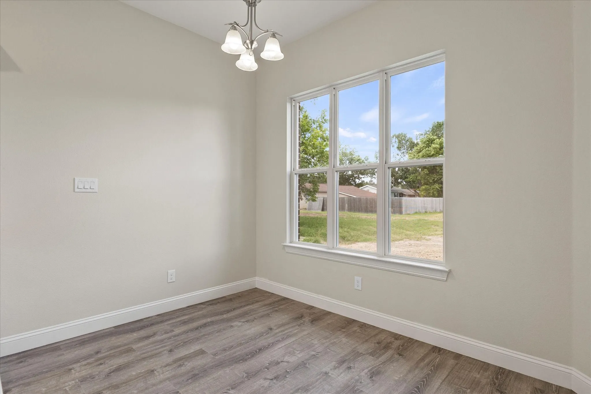 Empty room with a chandelier, healthy amount of natural light, and wood finished floors