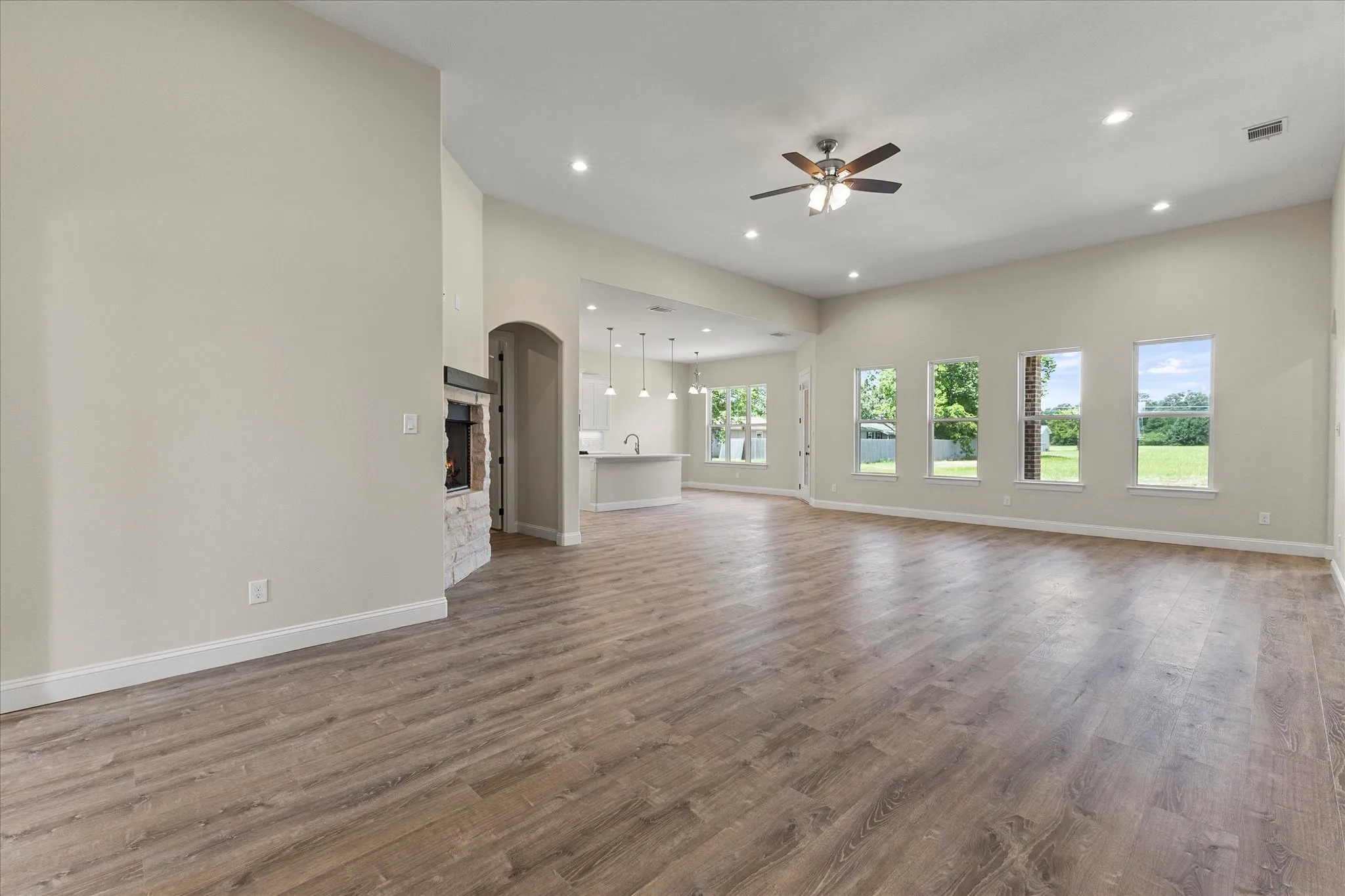 Unfurnished living room featuring ceiling fan, recessed lighting, wood finished floors, and arched walkways