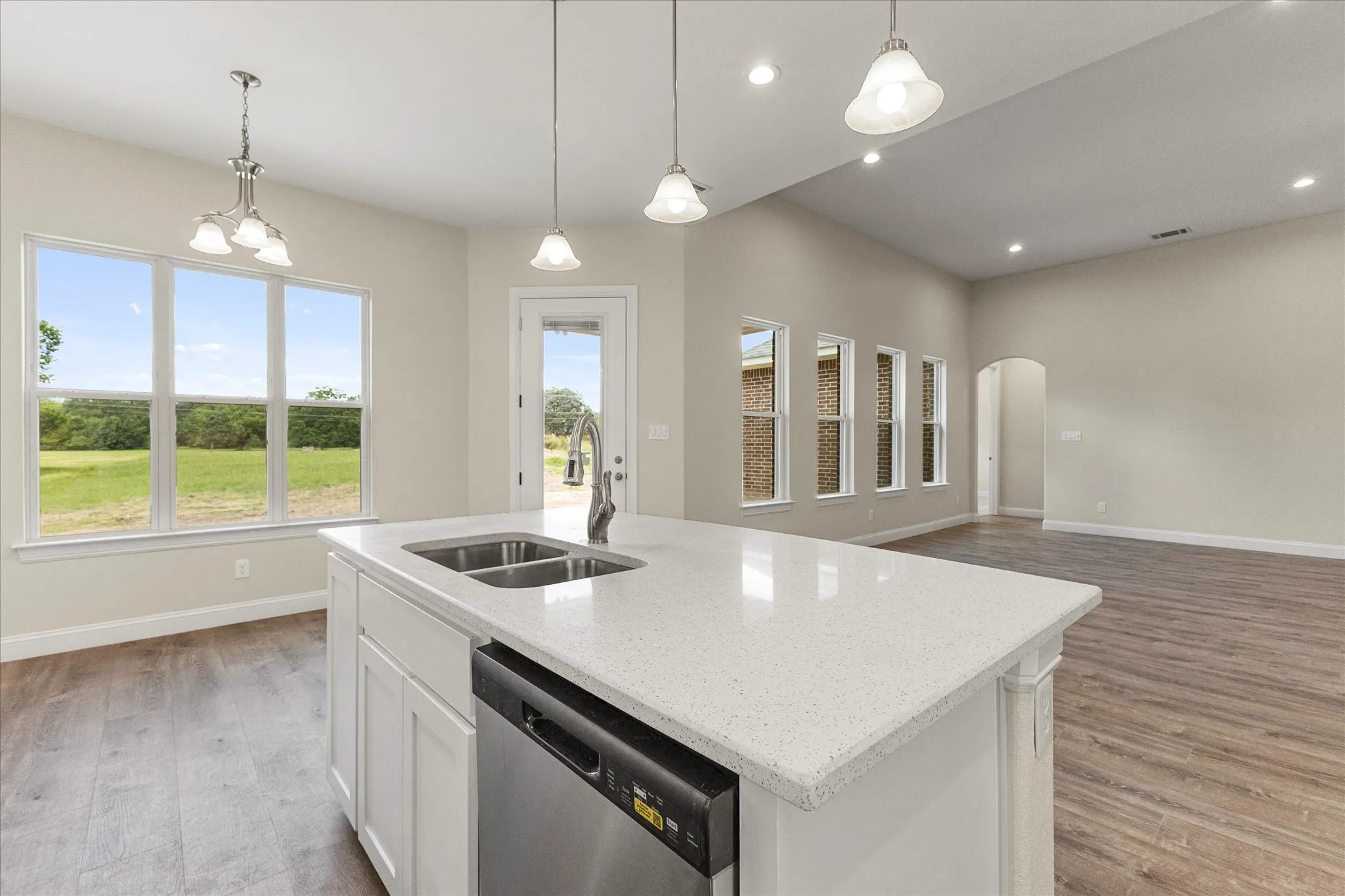 Kitchen with dishwasher, healthy amount of natural light, light wood-style flooring, arched walkways, and recessed lighting