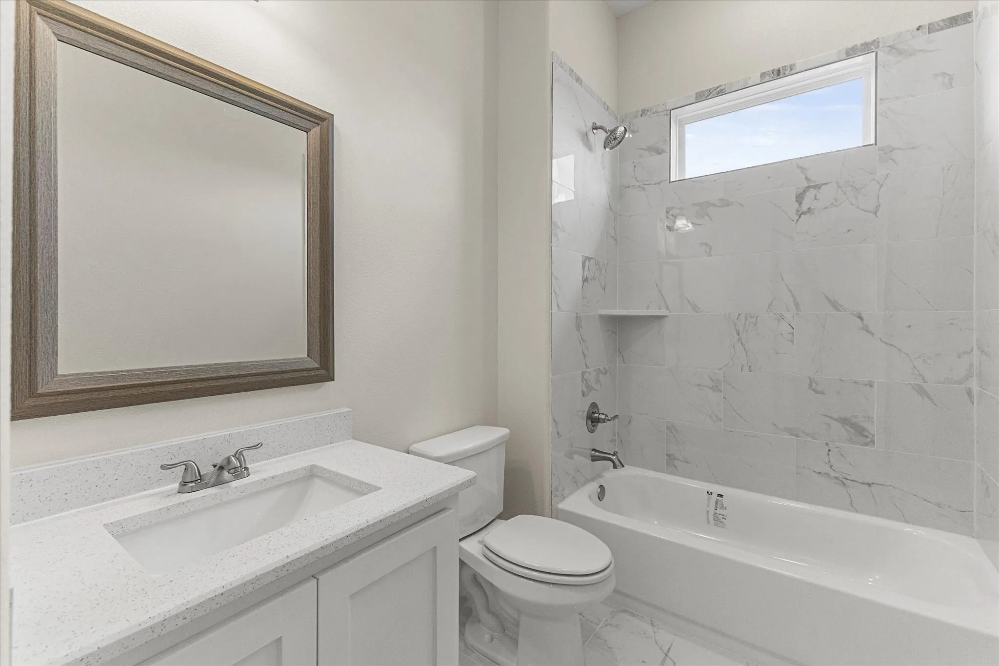 Full bathroom featuring marble finish floors, vanity, and washtub / shower combination