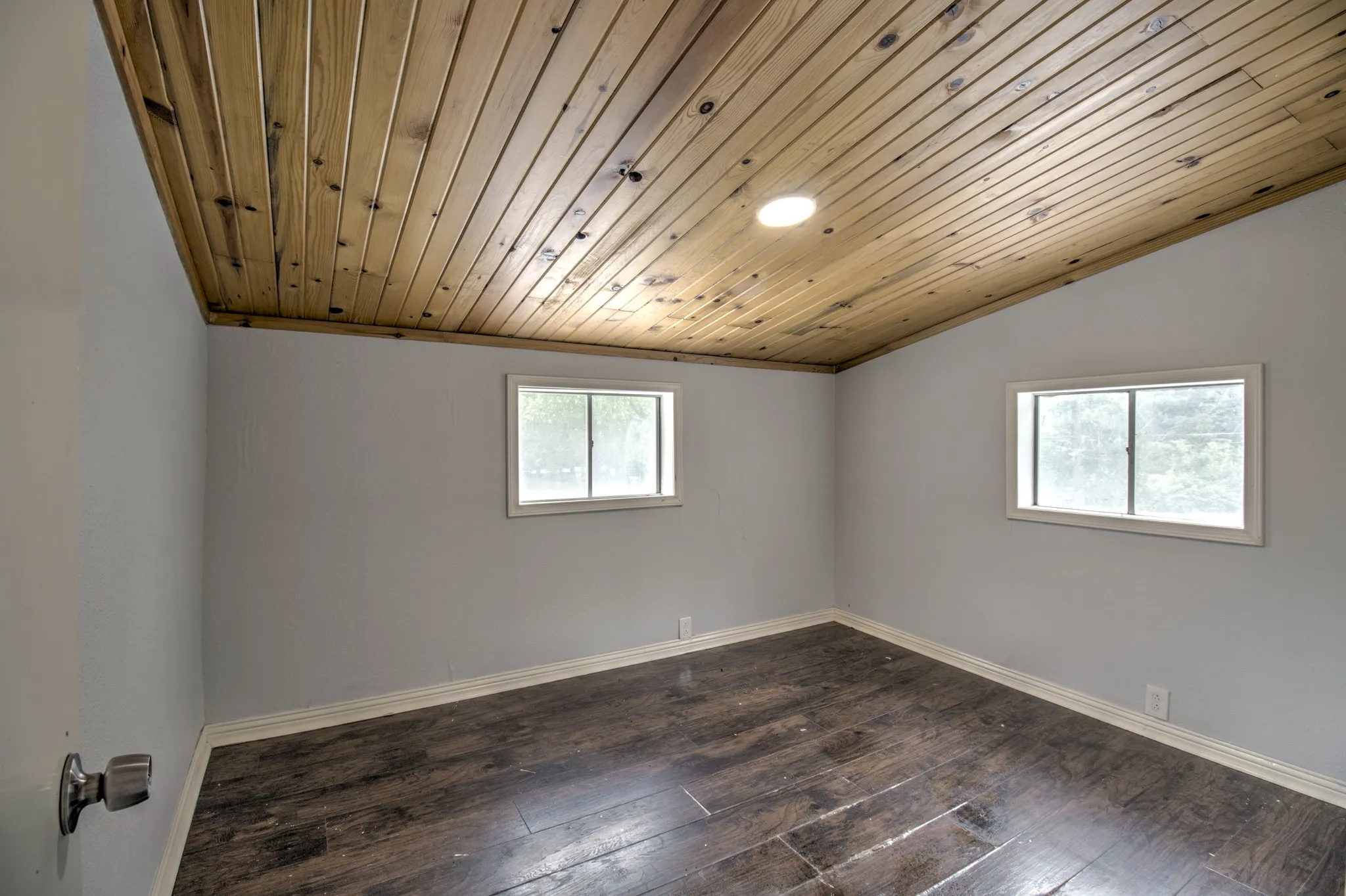 Empty room featuring baseboards, dark wood finished floors, and vaulted ceiling
