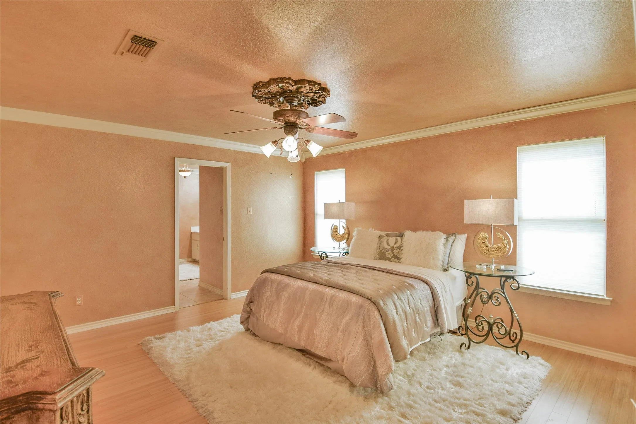 Bedroom featuring wood finished floors, a textured ceiling, ornamental molding, baseboards, and a ceiling fan