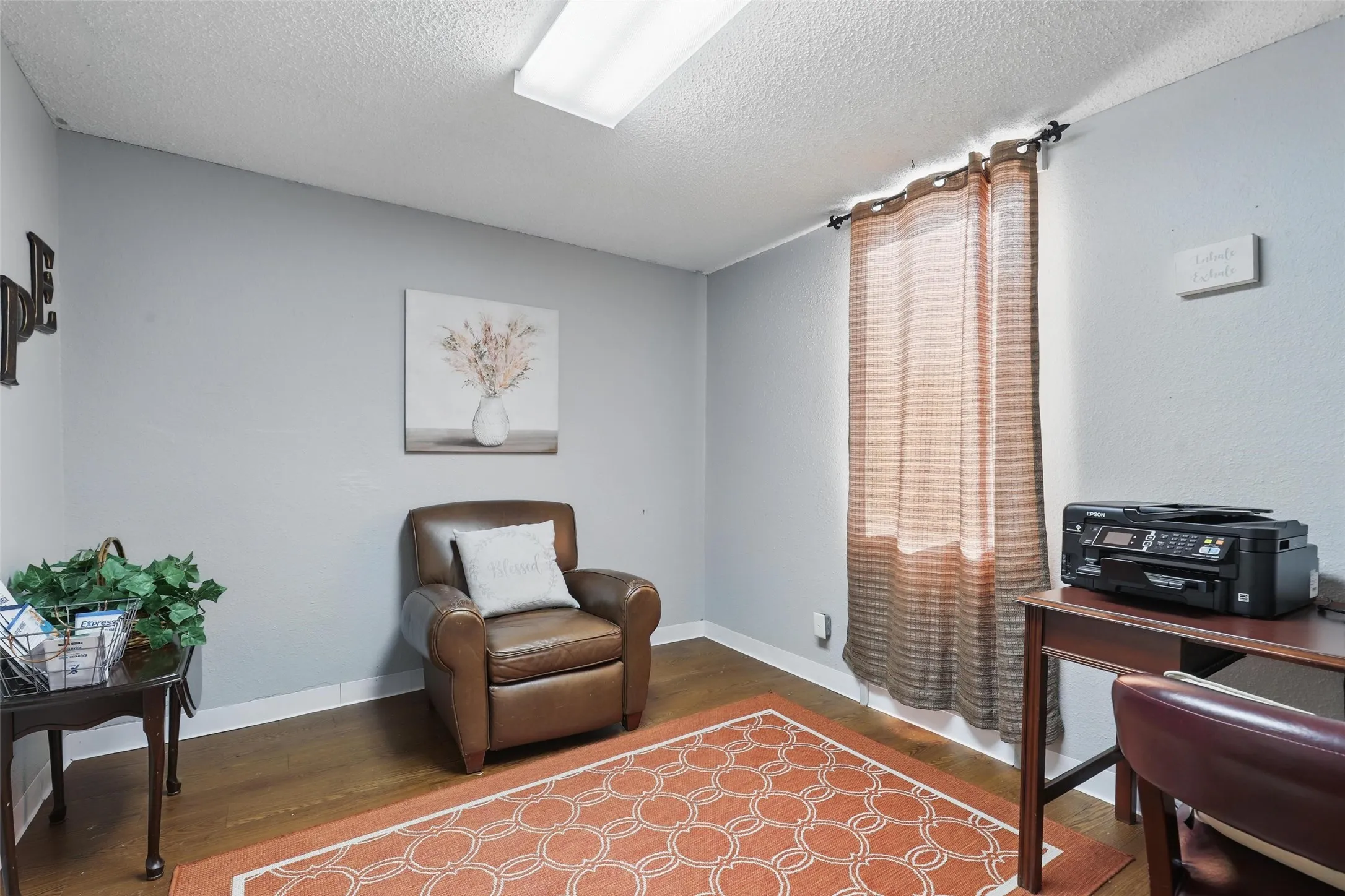 Home office with wood finished floors, a textured ceiling, and baseboards