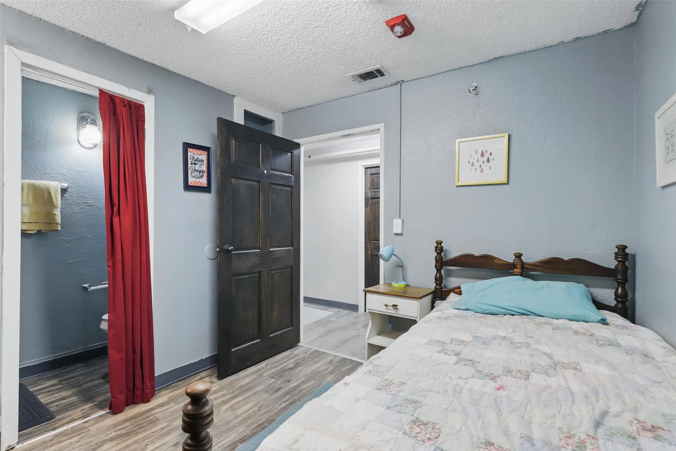 Bedroom with wood finished floors, a textured ceiling, and baseboards