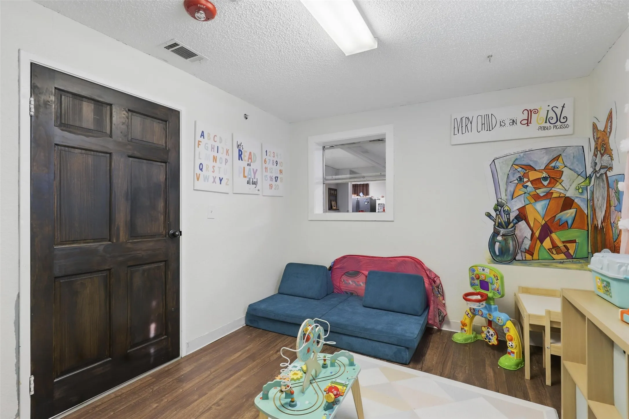Living area featuring wood finished floors, a textured ceiling, and baseboards