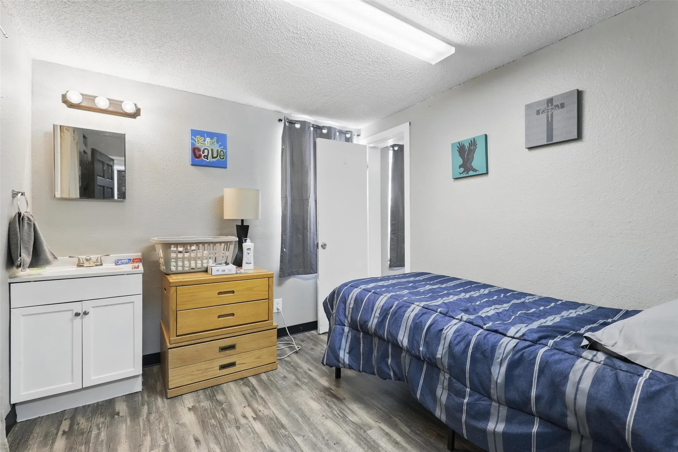 Bedroom featuring a textured ceiling, wood finished floors, and a sink