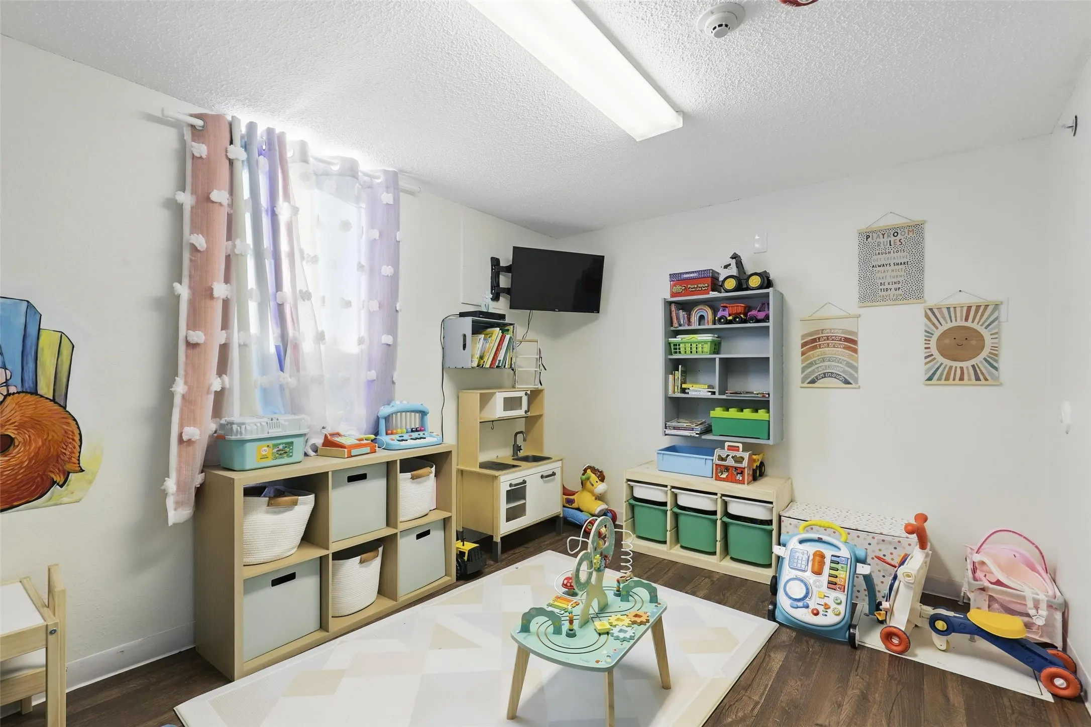 Game room featuring dark wood-style flooring, a textured ceiling, and baseboards