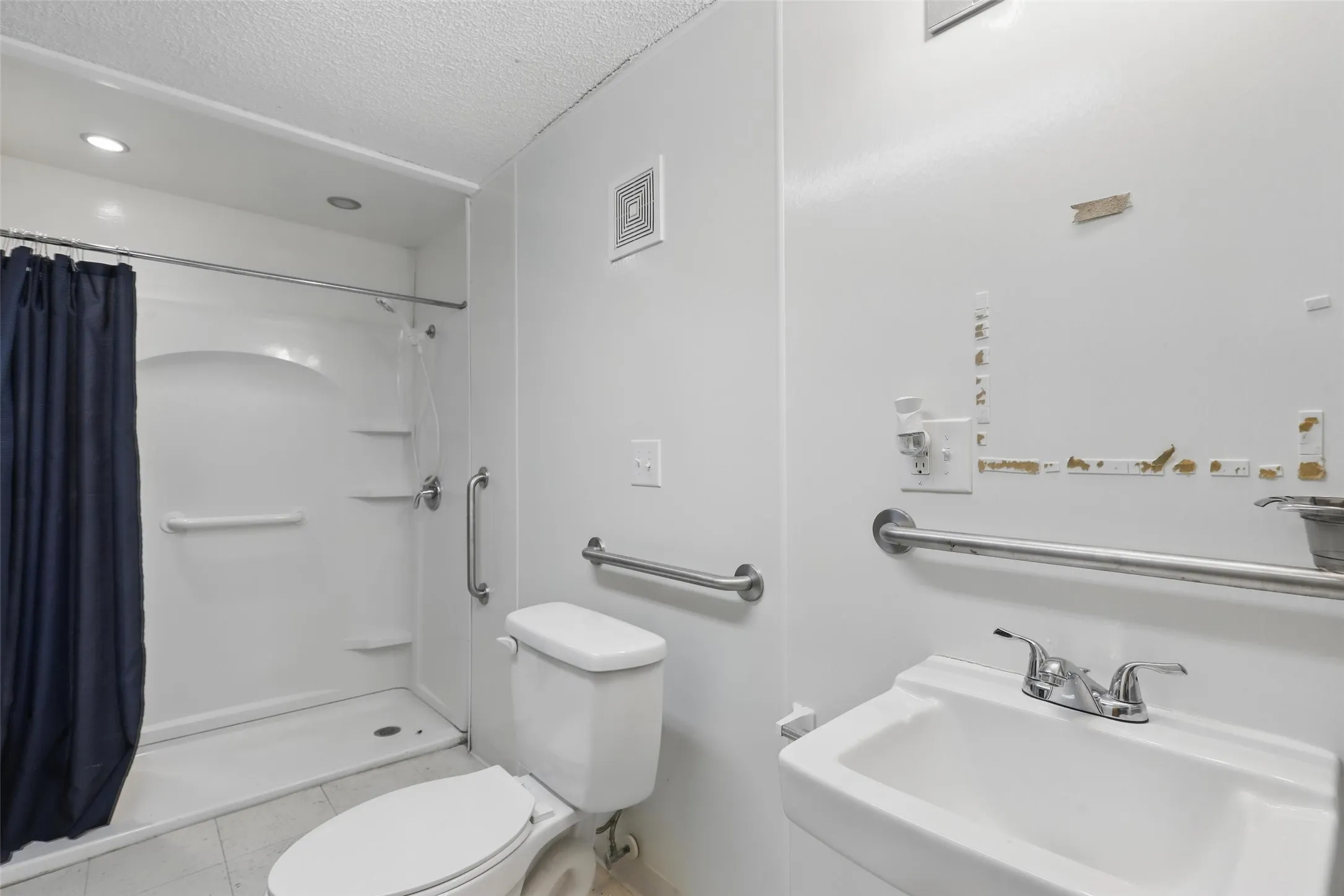 Bathroom with toilet, a textured ceiling, tile patterned flooring, a shower with curtain, and a sink