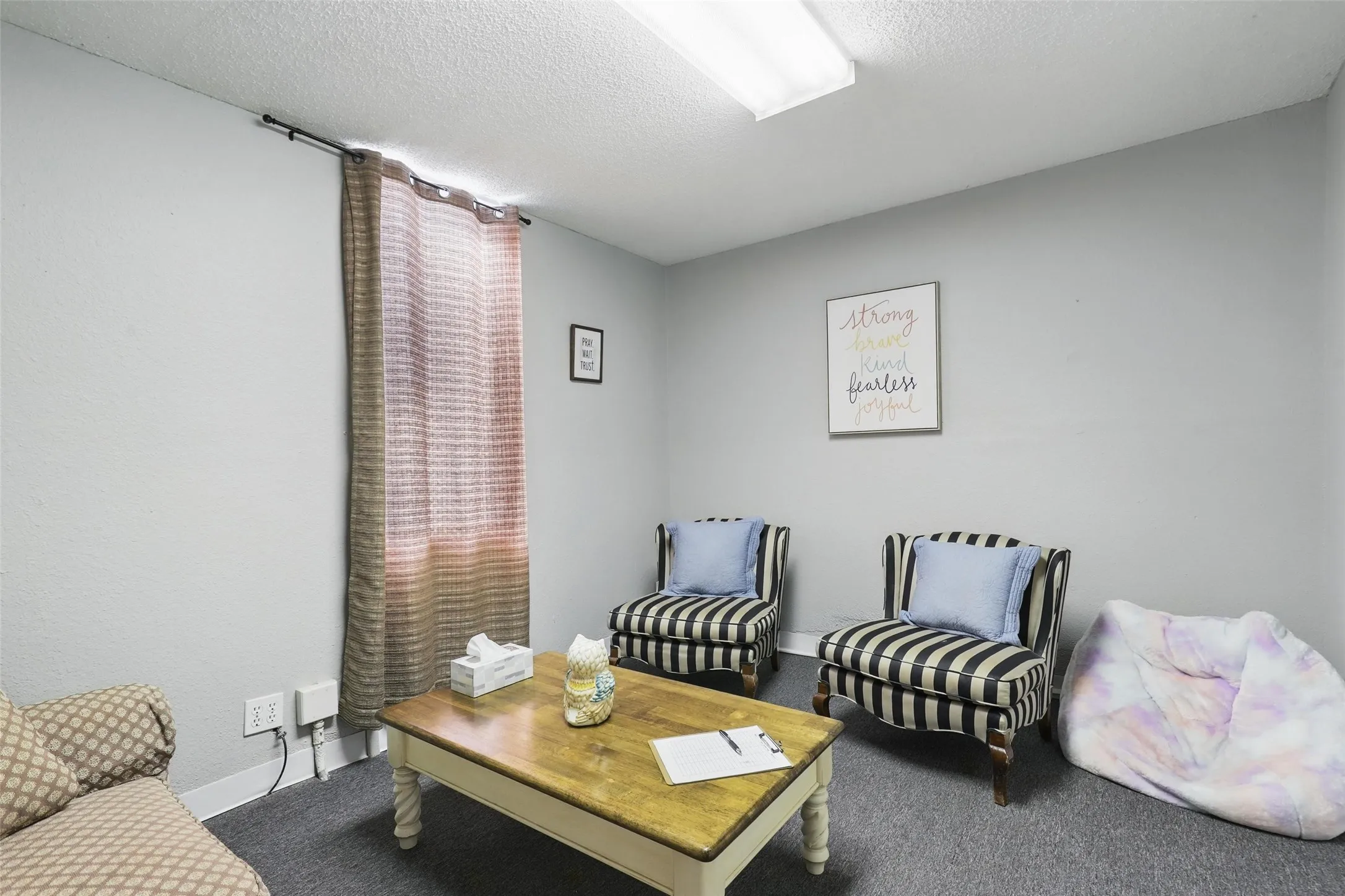 Living area with carpet flooring, baseboards, and a textured ceiling
