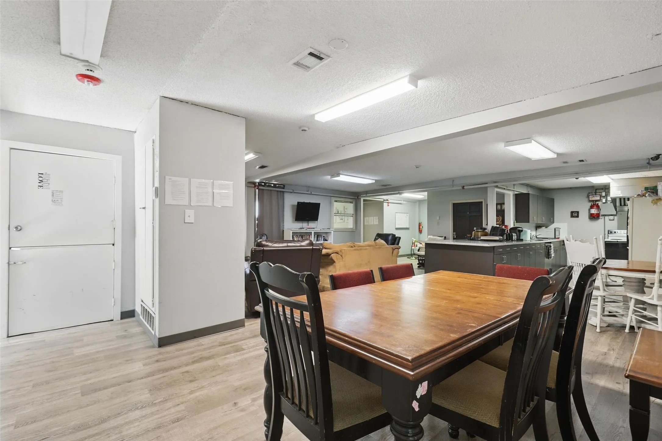 Dining room with light wood-type flooring, a textured ceiling, and baseboards