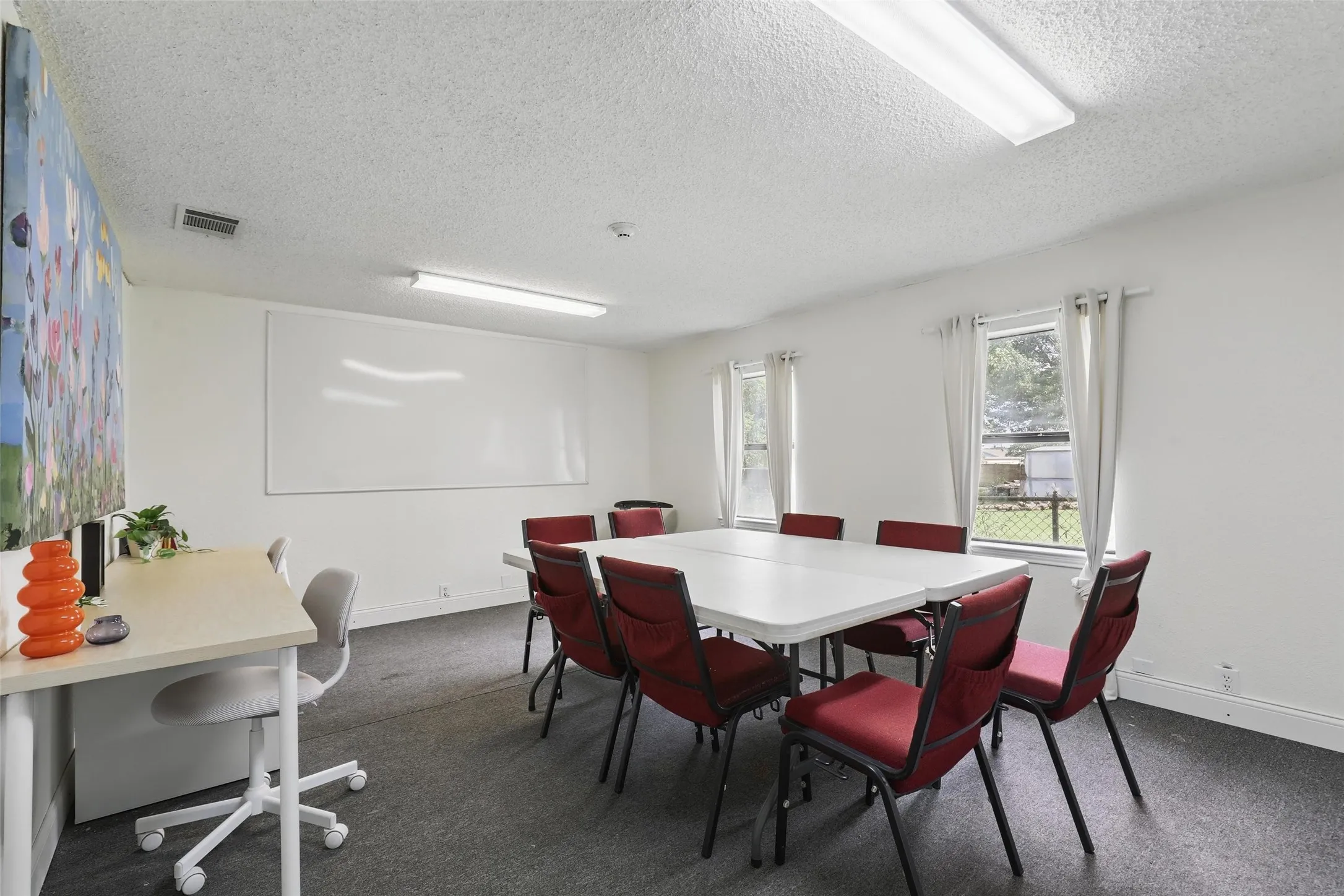 Dining room with a textured ceiling, baseboards, a desk, and dark colored carpet