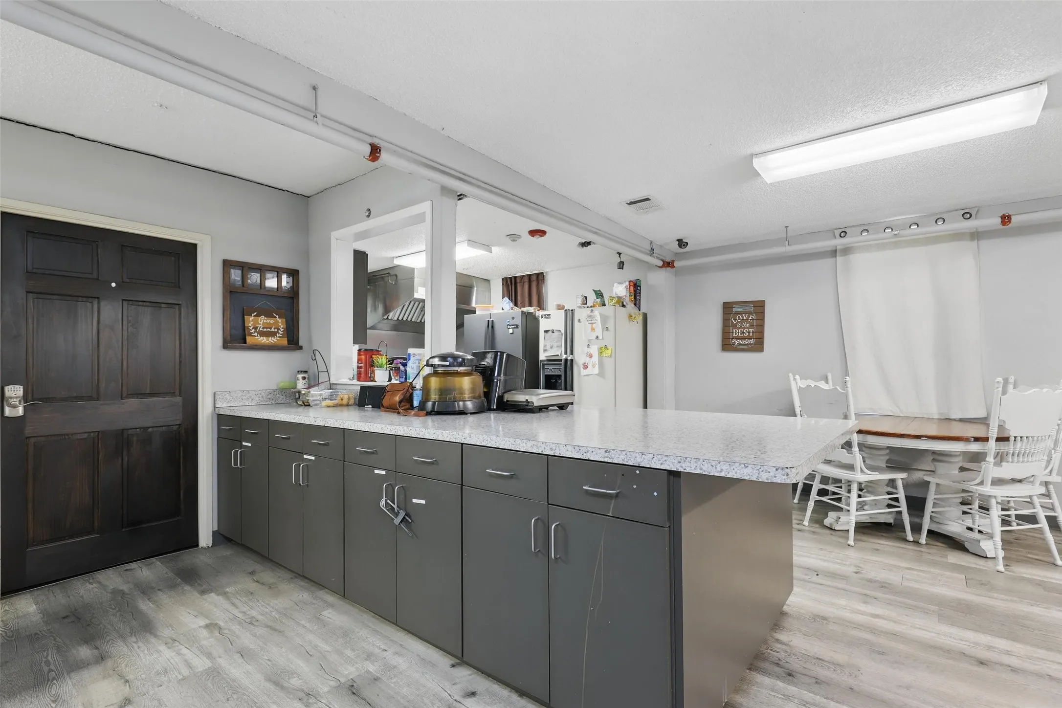 Kitchen featuring a peninsula, light wood finished floors, white refrigerator with ice dispenser, and light countertops