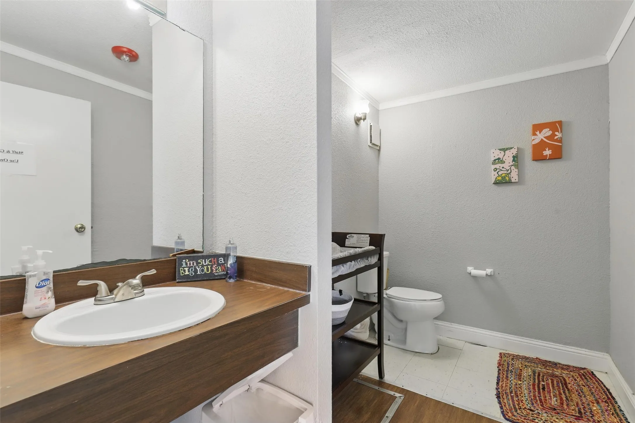 Bathroom featuring ornamental molding, toilet, vanity, baseboards, and a textured ceiling