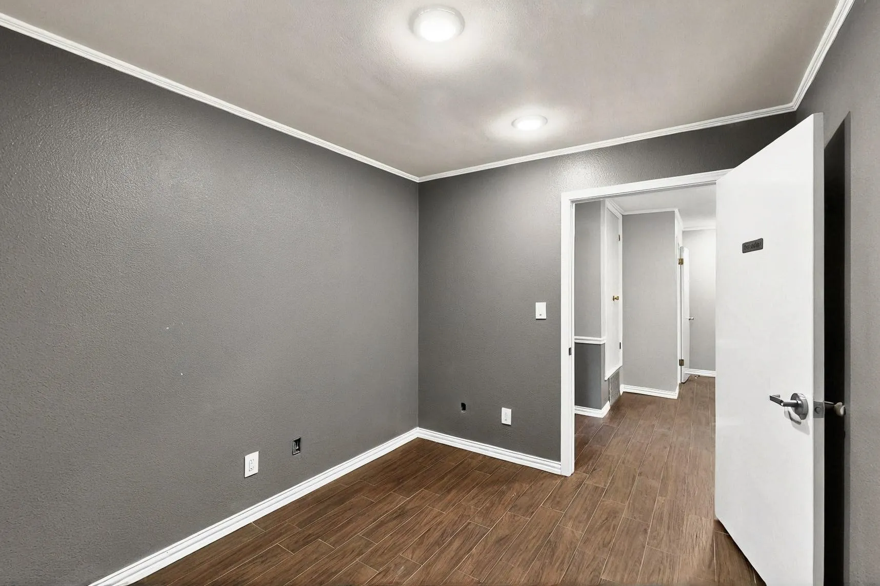 Spare room with ornamental molding, wood finished floors, and baseboards