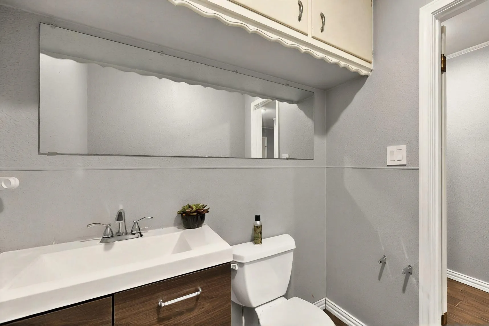 Half bathroom featuring toilet, vanity, baseboards, and wood finished floors