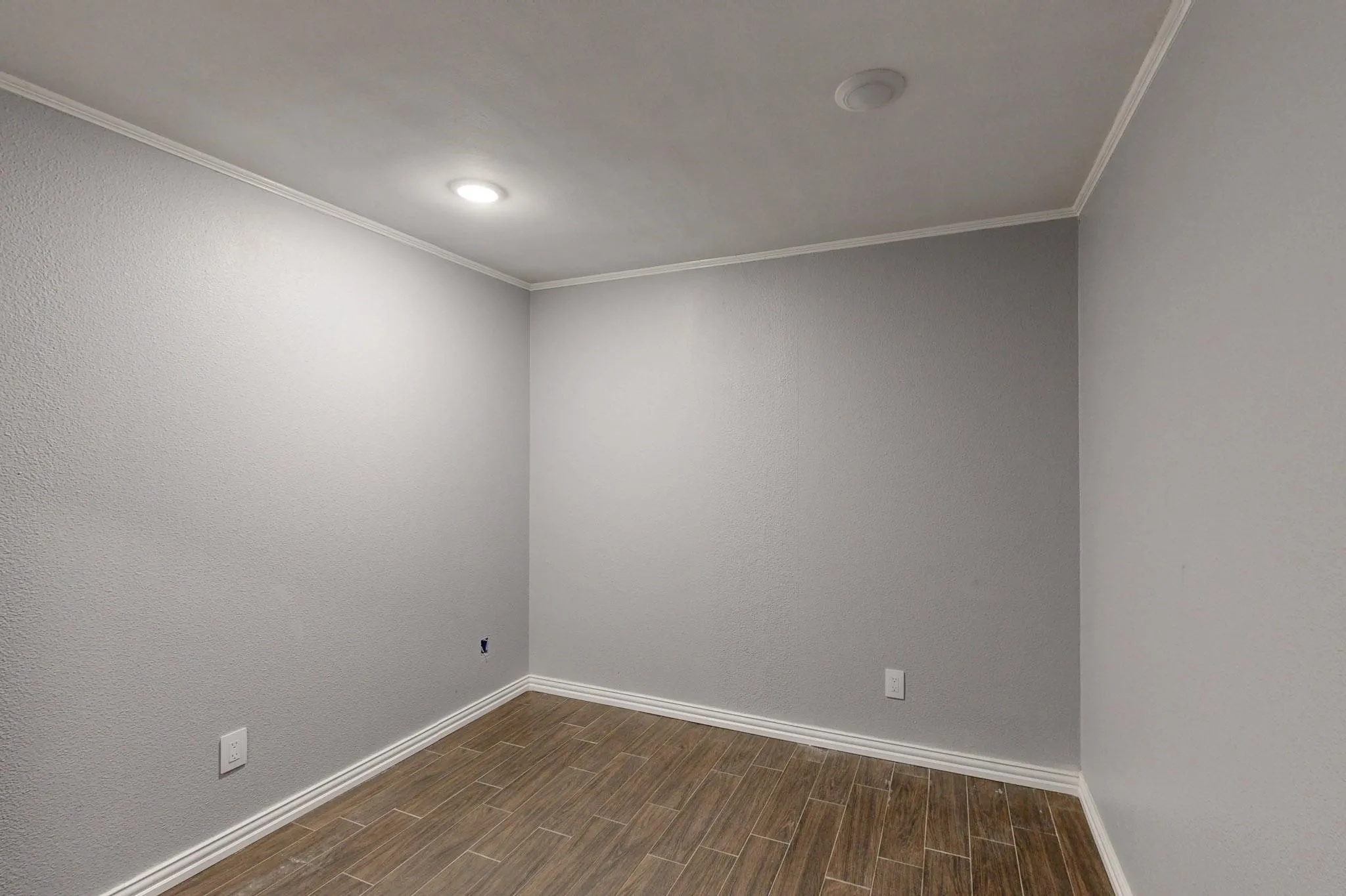 Spare room featuring wood finish floors, baseboards, crown molding, and recessed lighting