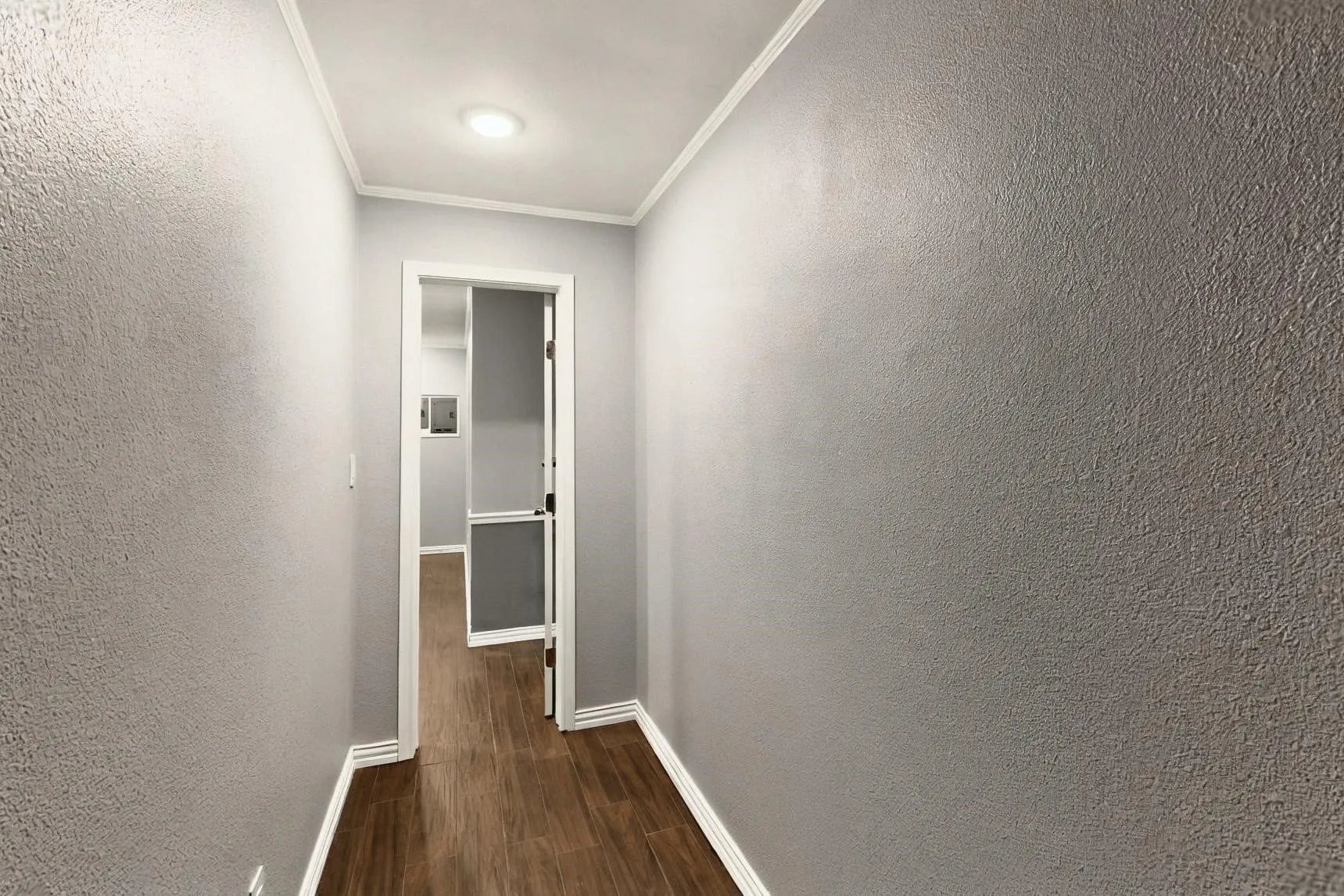 Hall with baseboards, dark wood-style floors, ornamental molding, and a textured wall