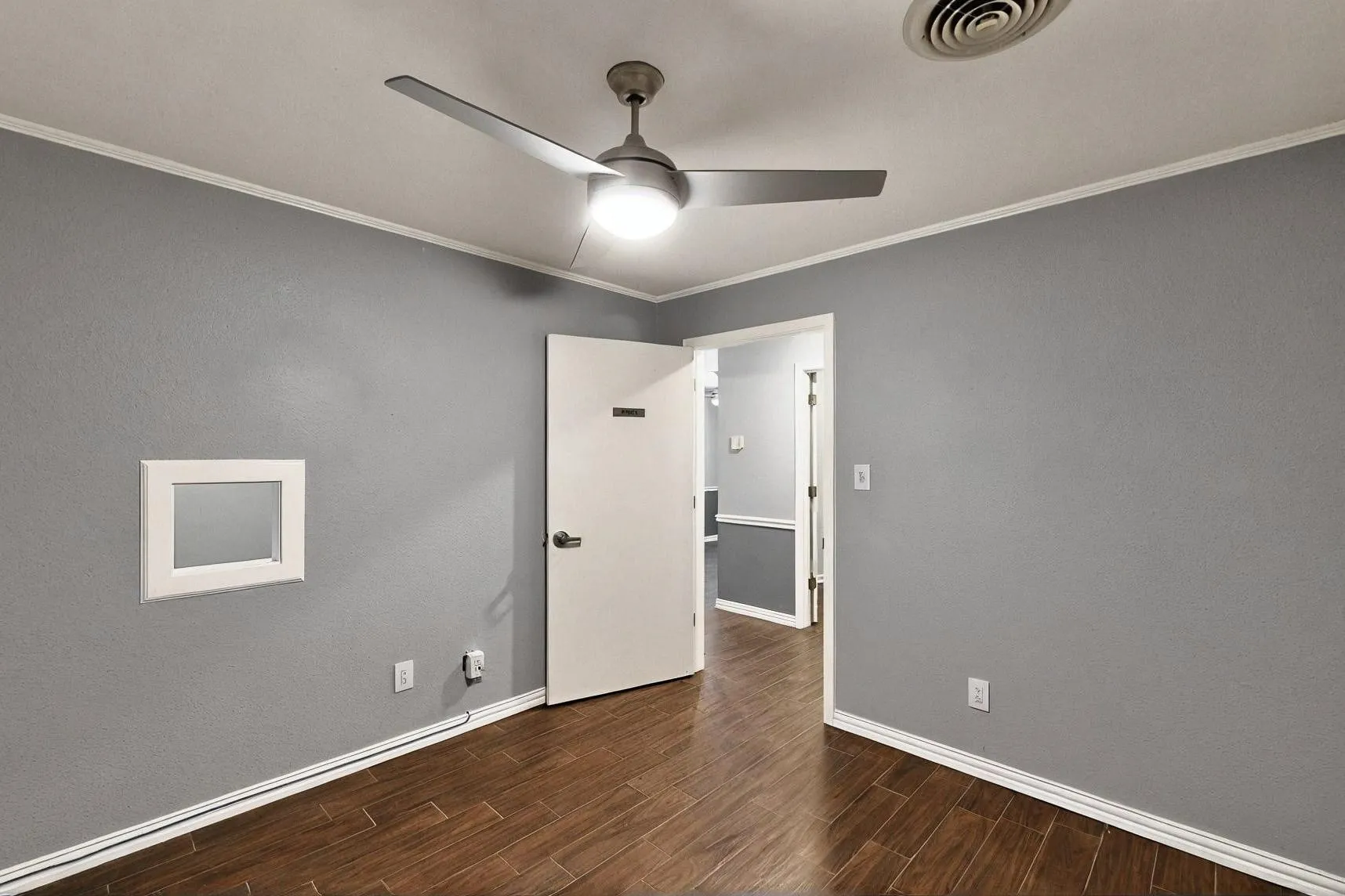 Unfurnished room featuring ceiling fan, wood finished floors, baseboards, and ornamental molding