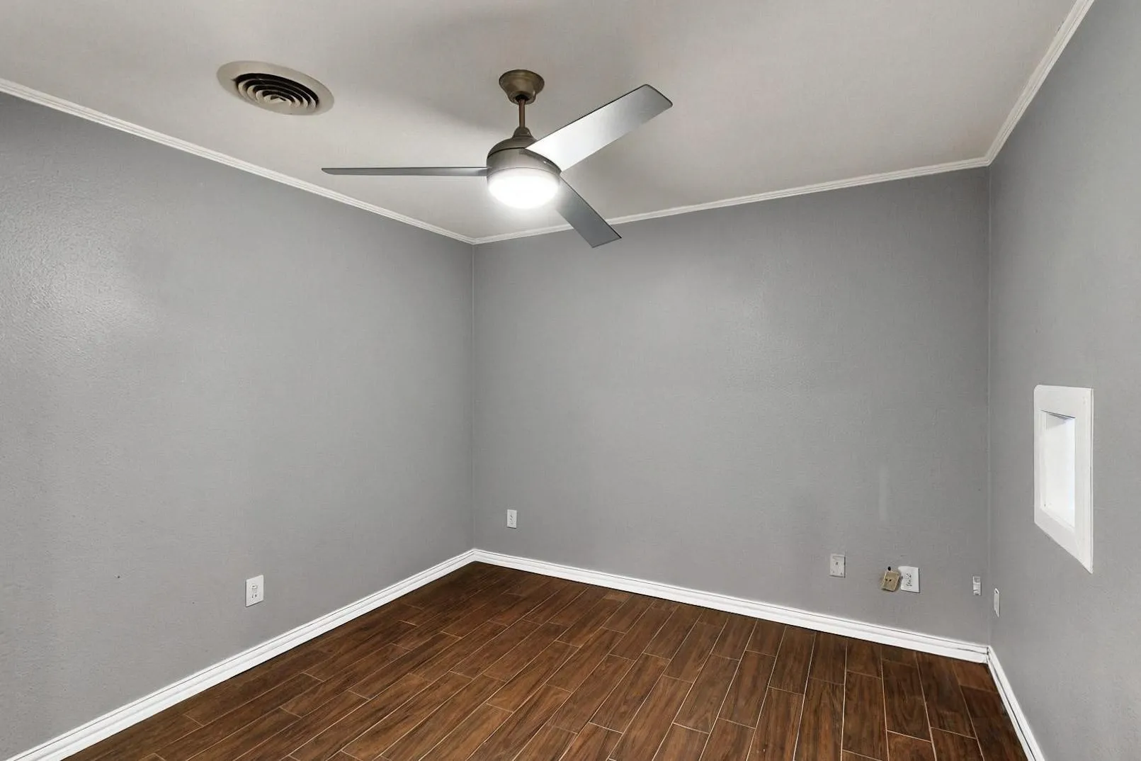 Empty room featuring a ceiling fan, baseboards, dark wood-style flooring, and ornamental molding