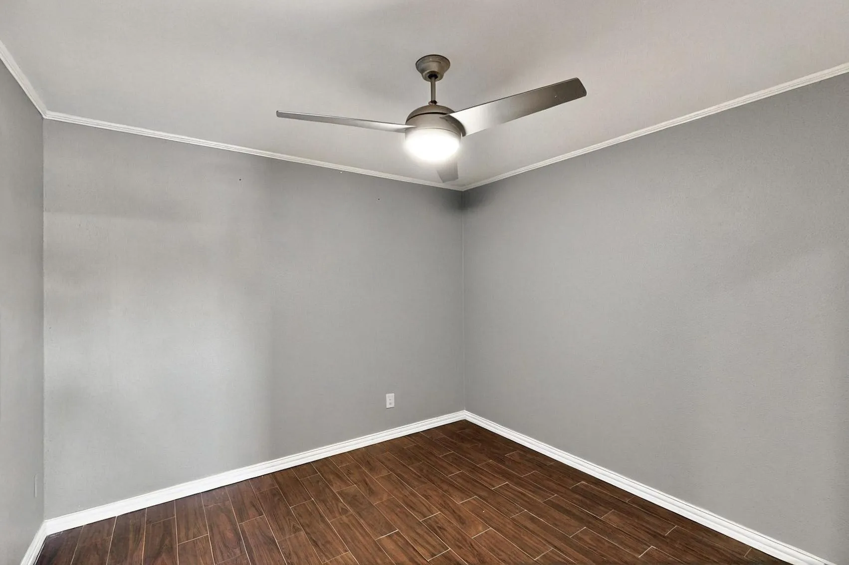 Empty room with ceiling fan, baseboards, wood finish floors, and ornamental molding