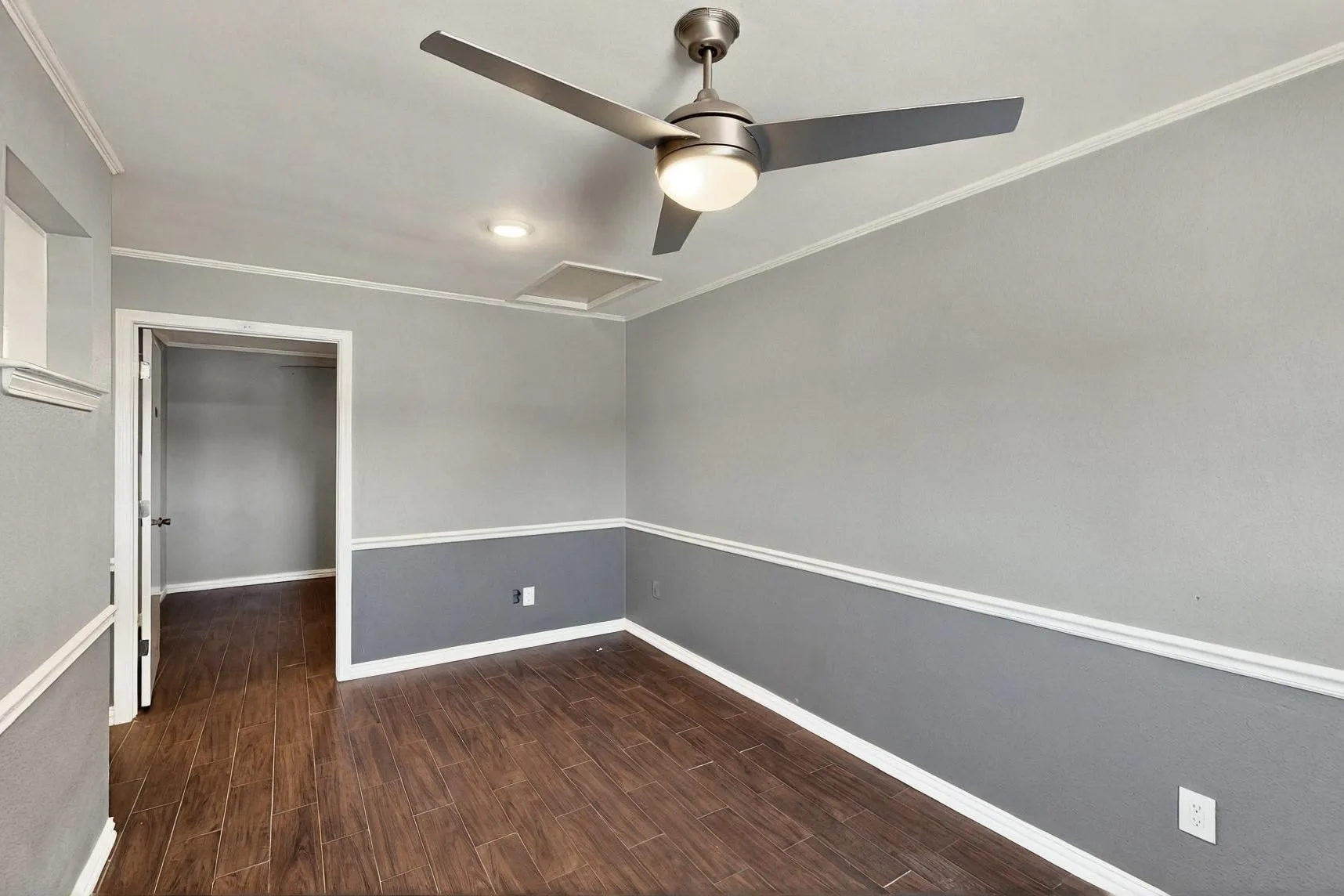 Spare room featuring ceiling fan, crown molding, wood finished floors, and baseboards