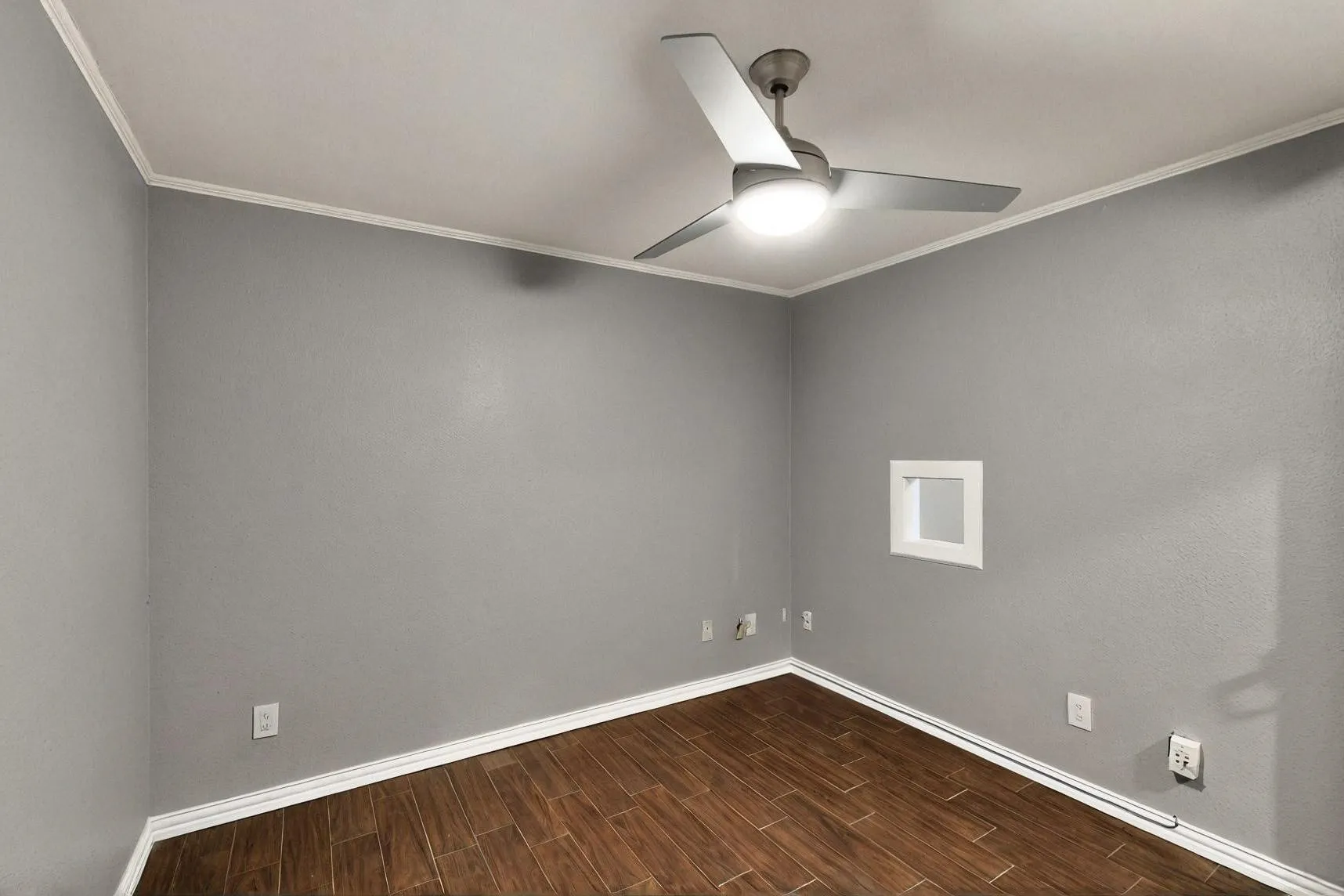 Spare room featuring a ceiling fan, baseboards, wood finish floors, and ornamental molding
