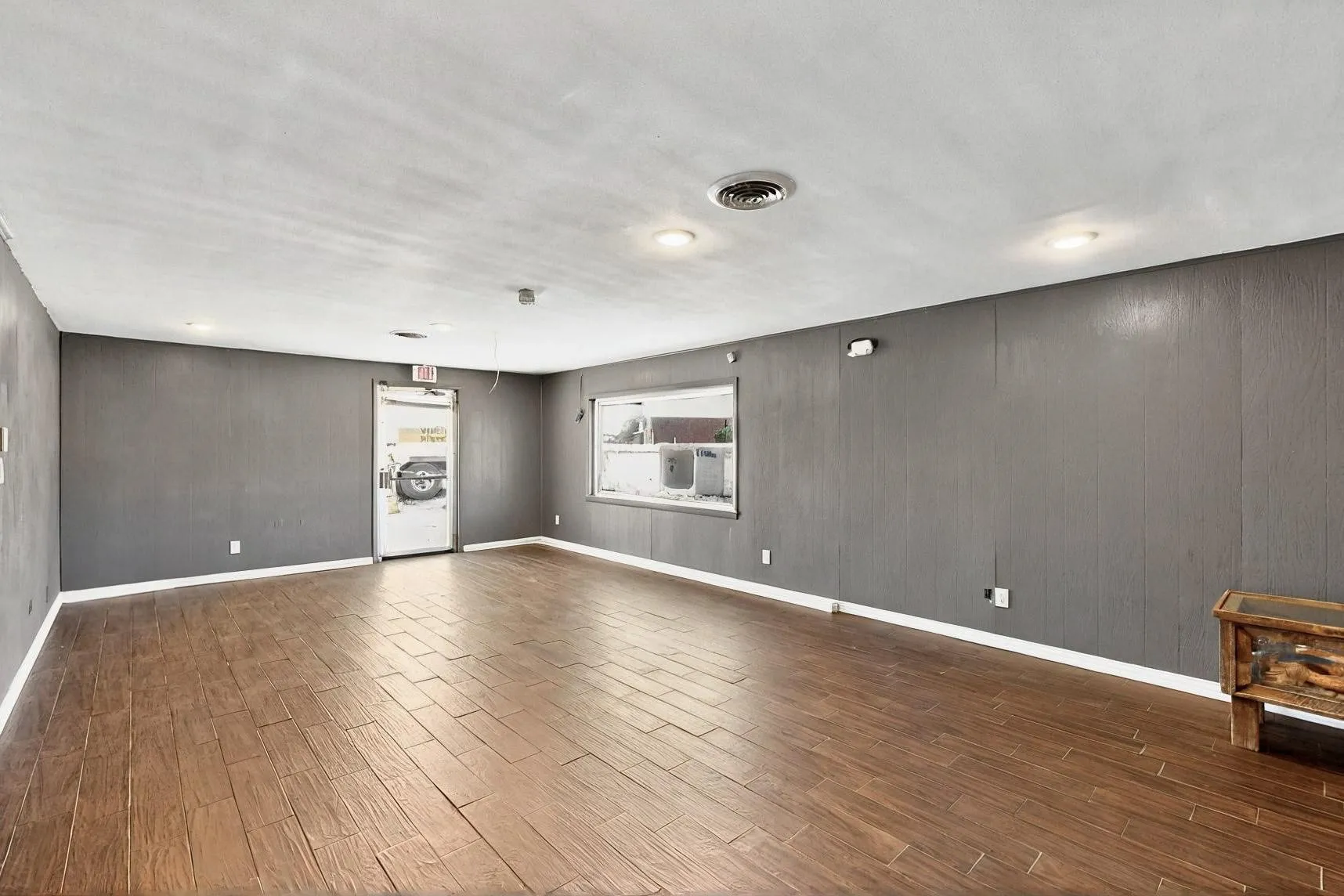 Spare room featuring dark wood-style floors and baseboards