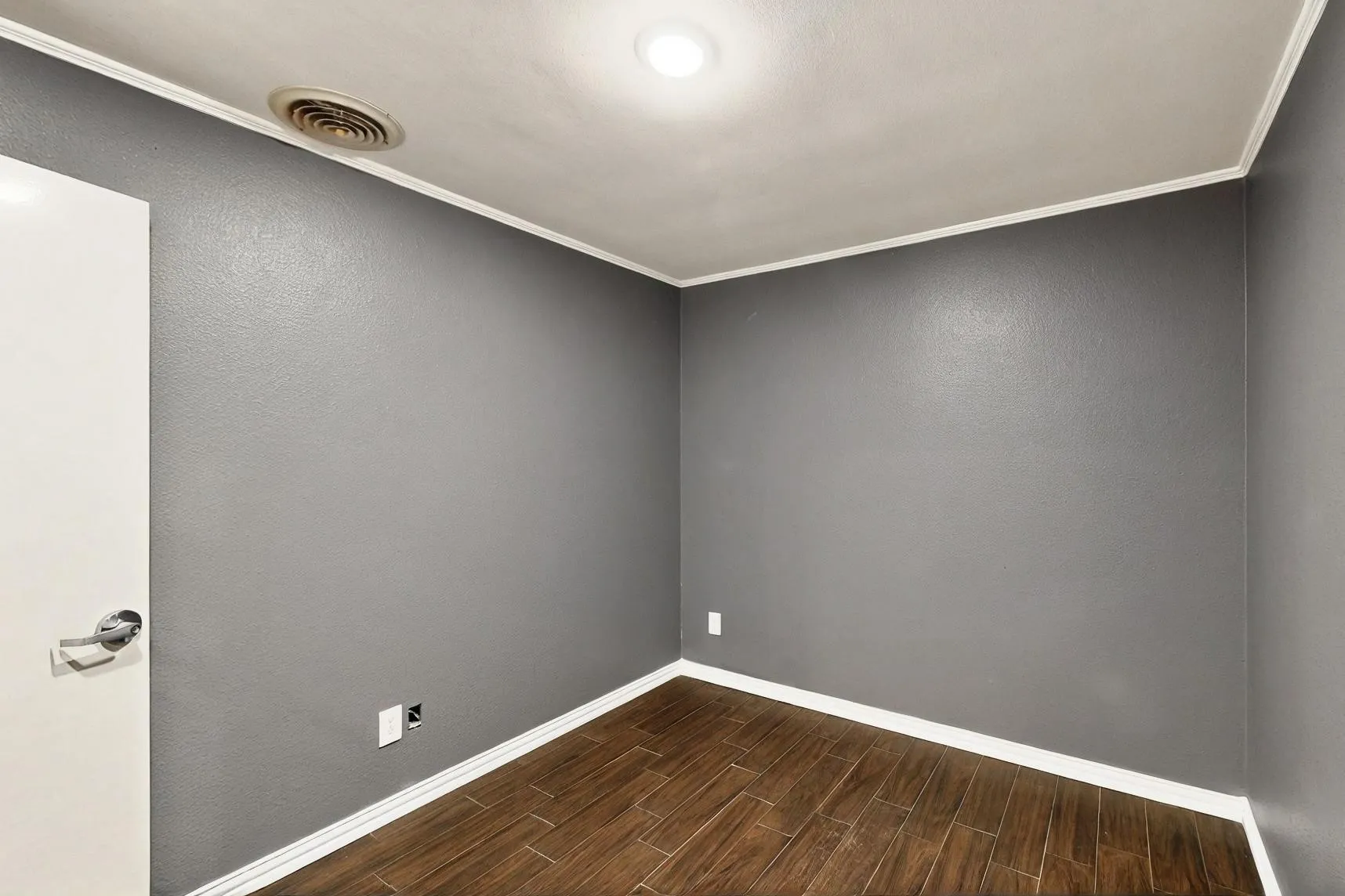 Spare room featuring dark wood finished floors, baseboards, and ornamental molding