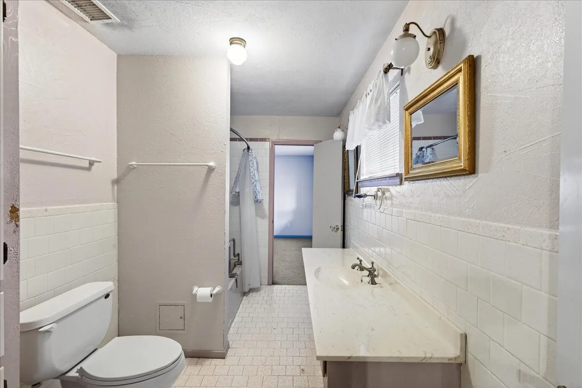Bathroom featuring a shower with shower curtain, vanity, tile walls, tile patterned flooring, and a wainscoted wall