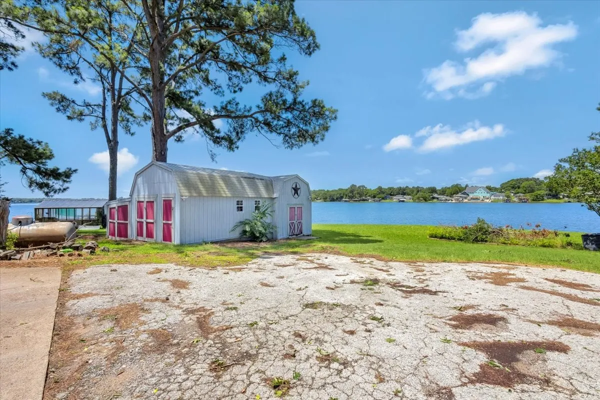 View of green lawn with a water view and a storage unit