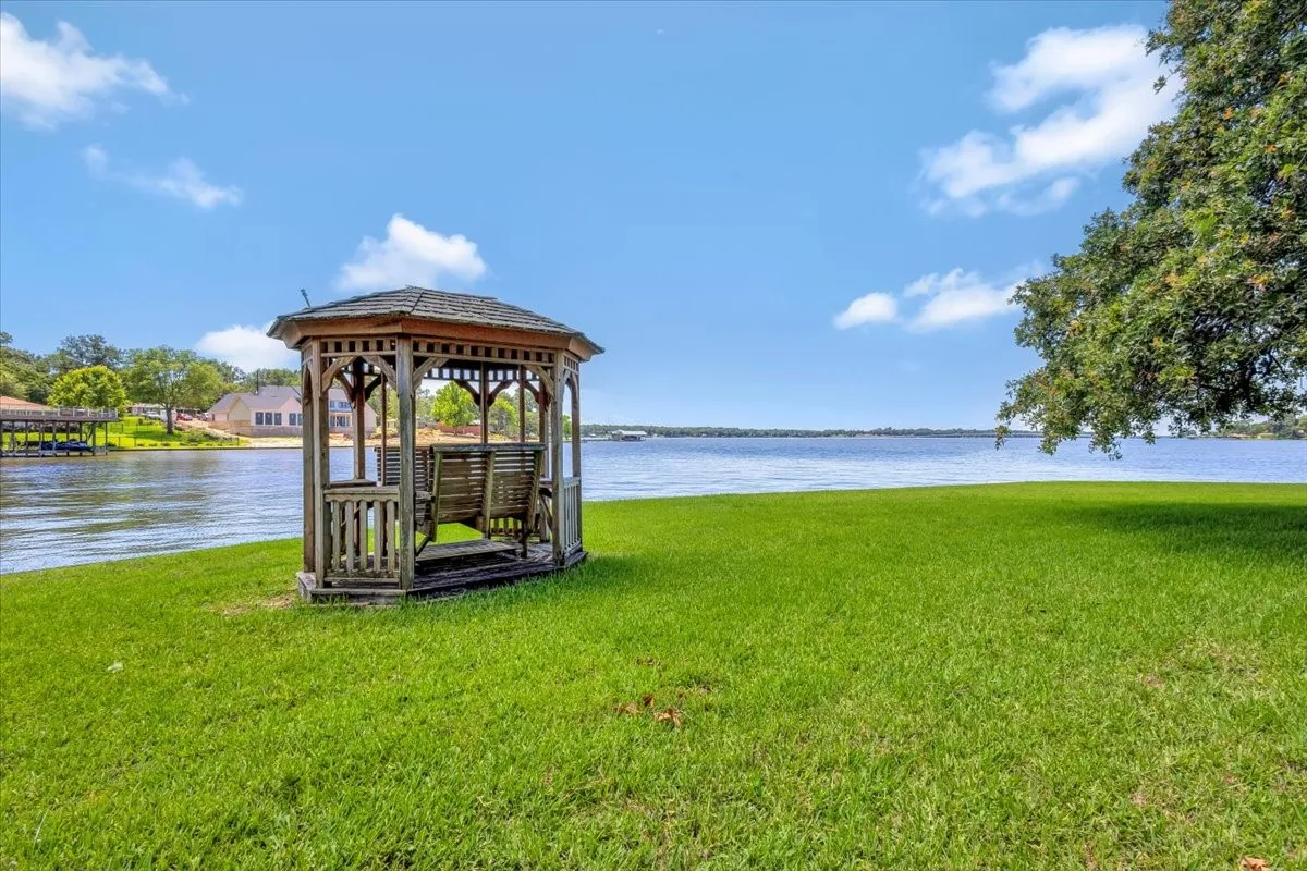Dock featuring a gazebo, a water view, and a lawn