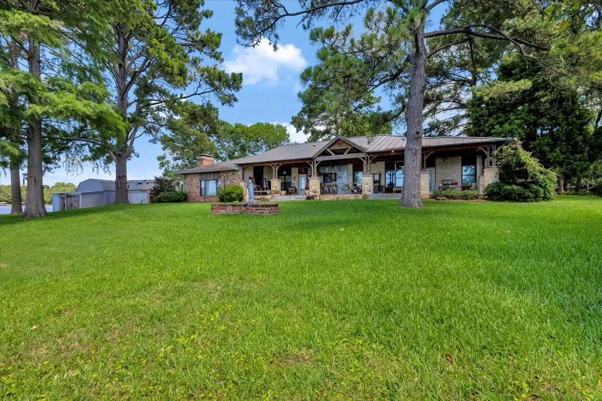 Back of house featuring a yard, a chimney, and a metal roof