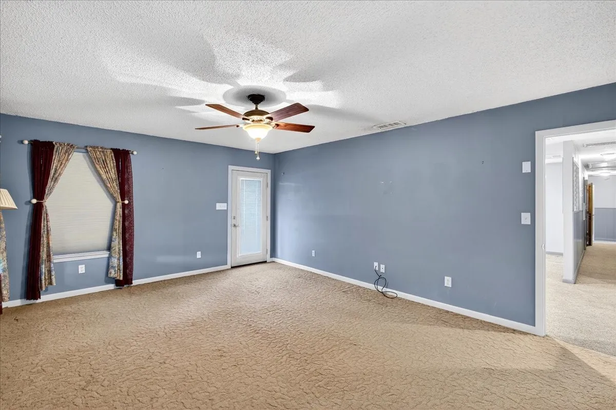 Spare room with carpet, a ceiling fan, and a textured ceiling