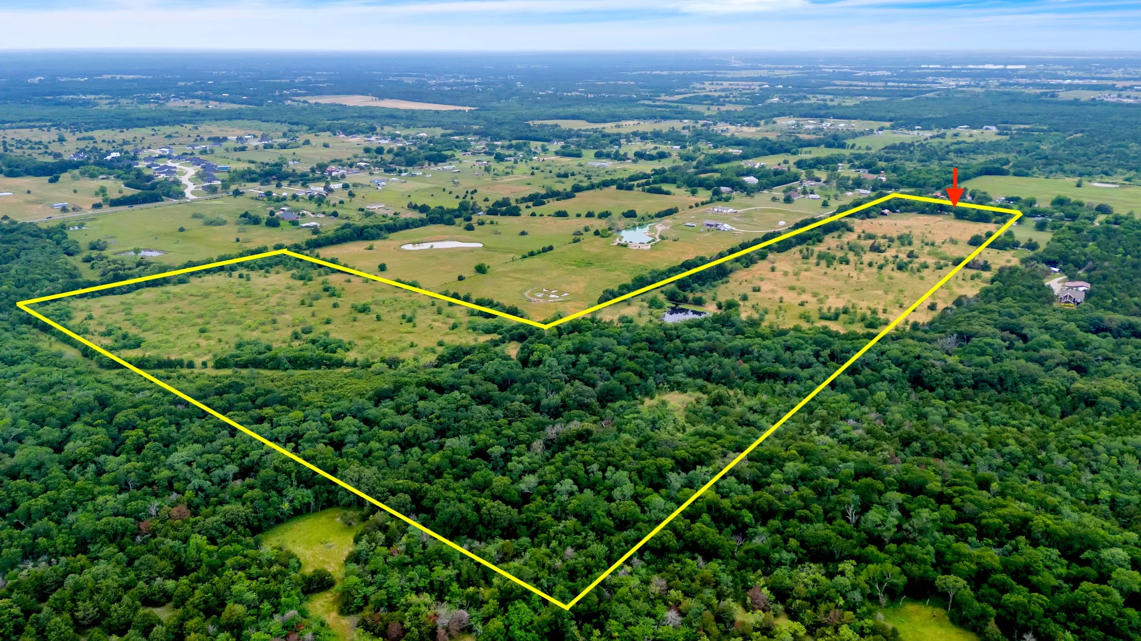 Aerial overview of property's location with property parcel outlined and a forest