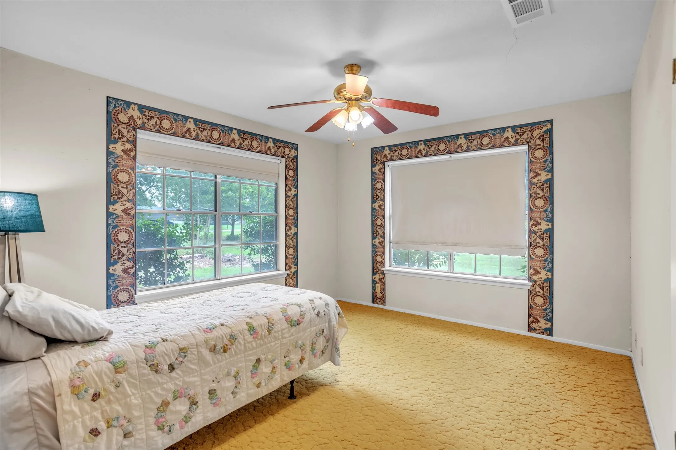 Carpeted bedroom with multiple windows, baseboards, and a ceiling fan