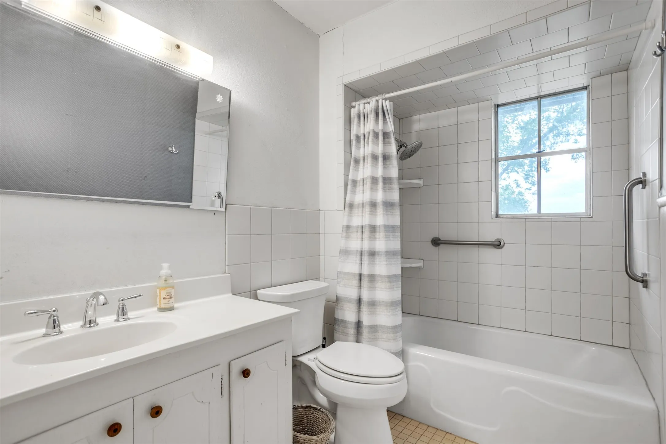 Full bathroom featuring toilet, shower / tub combo with curtain, vanity, and tile walls