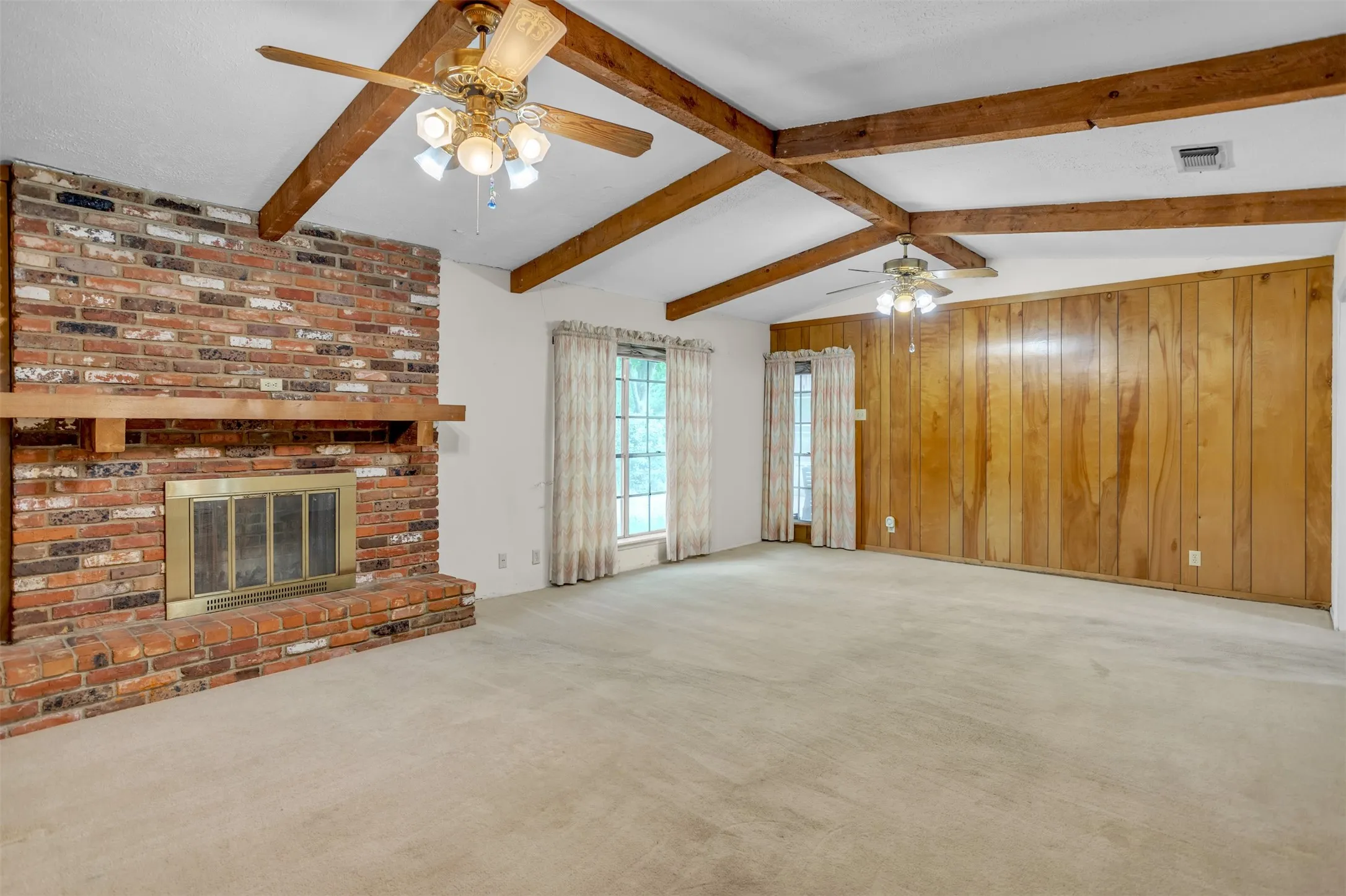 Unfurnished living room featuring ceiling fan, carpet, a brick fireplace