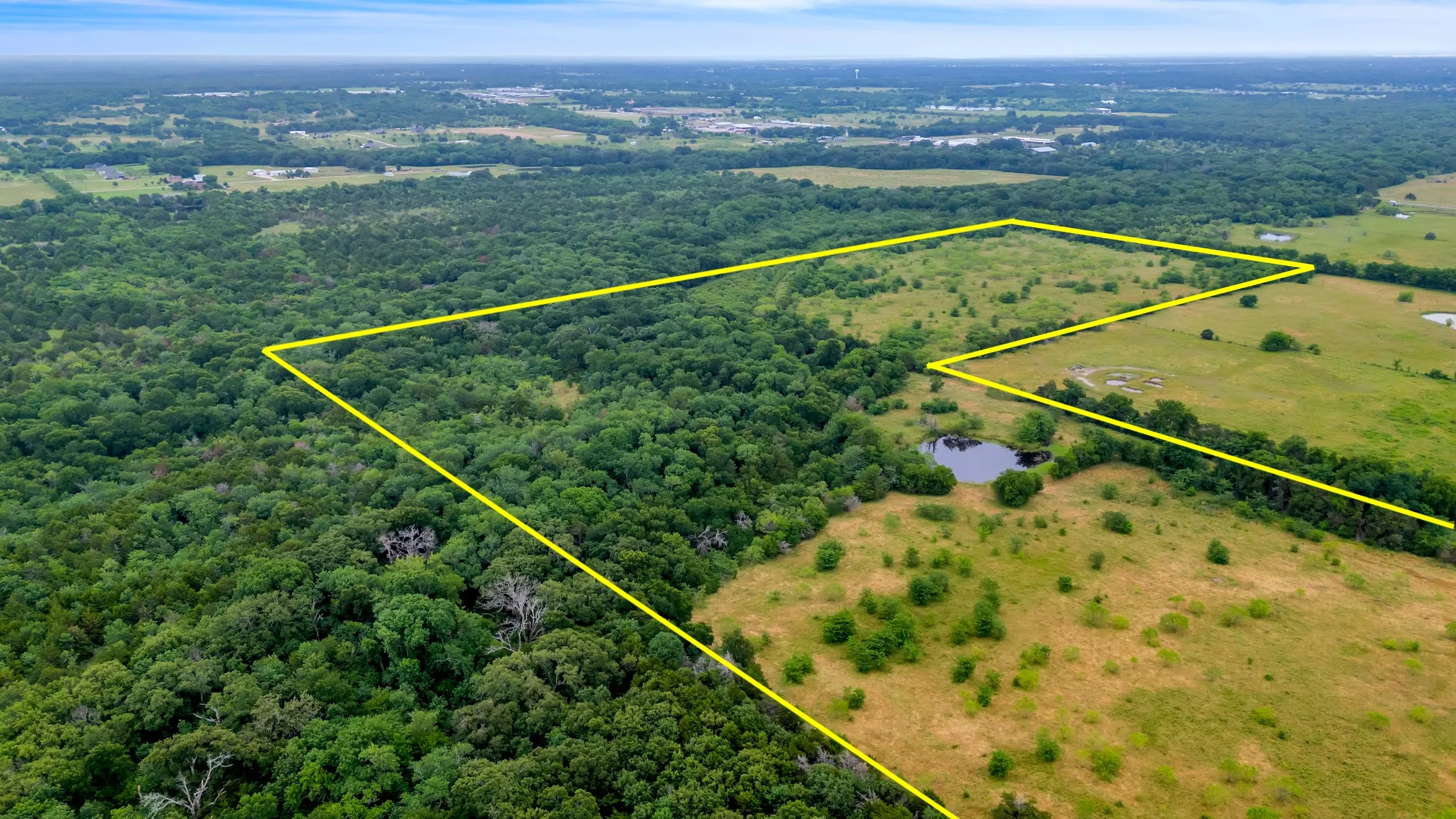 View of rural area with property parcel outlined and a forest