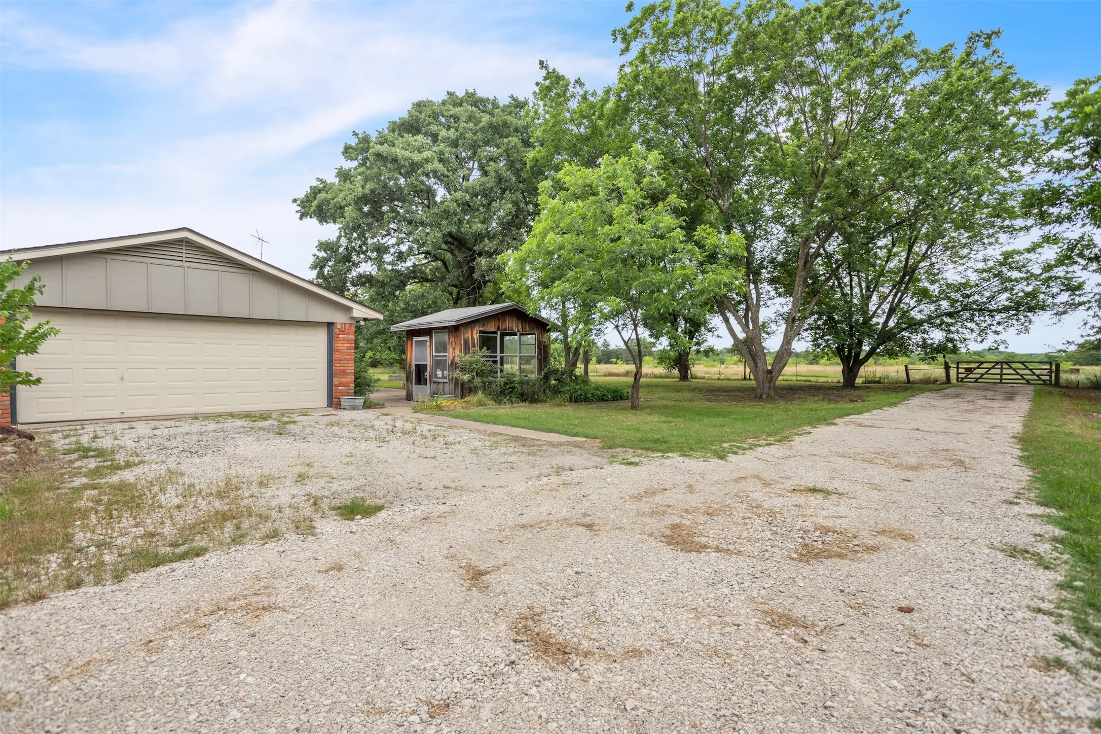 View of front of property featuring driveway, an outbuilding, board and batten siding, a garage, and brick siding