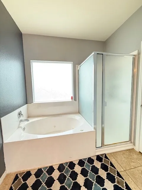 Bathroom with a shower stall, a jetted tub, and tile patterned floors