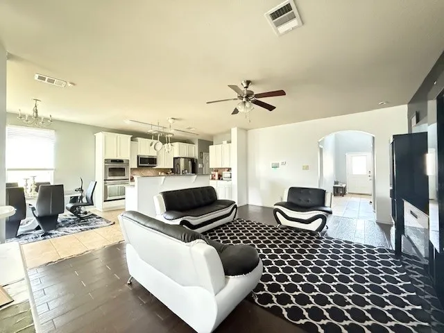 Living area with arched walkways, plenty of natural light, a ceiling fan, and light wood-style floors