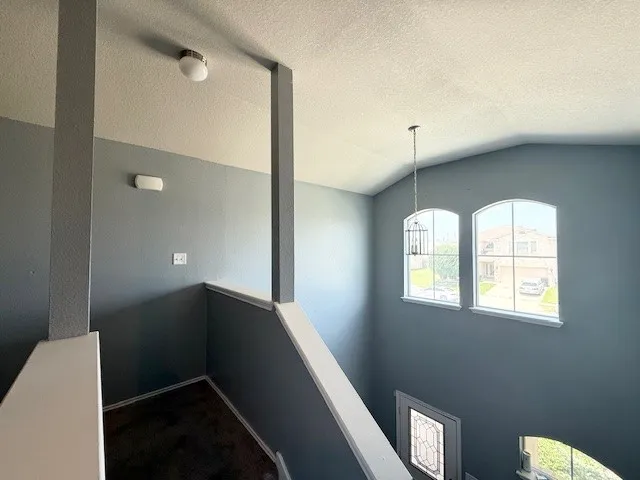 Stairs featuring plenty of natural light, vaulted ceiling, a textured ceiling, and carpet flooring