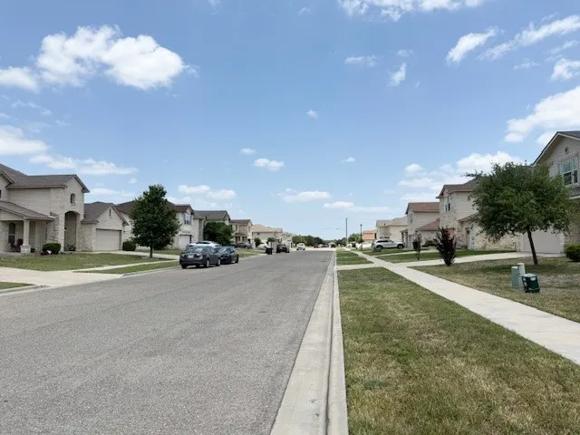View of asphalt road with a residential view, sidewalks, and curbs