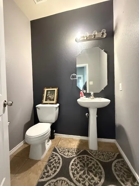 Bathroom with toilet, tile patterned floors, and baseboards