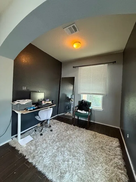 Office space featuring wood finished floors, baseboards, and arched walkways