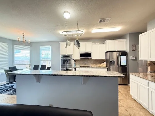 Kitchen featuring appliances with stainless steel finishes, tasteful backsplash, a kitchen breakfast bar, and a textured ceiling
