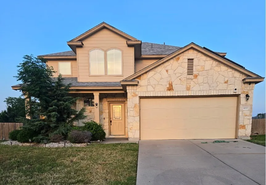 View of front of property with stone siding, concrete driveway, an attached garage, and a shingled roof