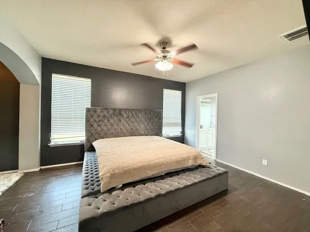 Bedroom featuring arched walkways, wood finished floors, and baseboards