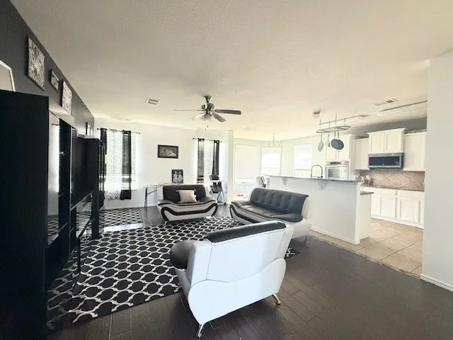 Living room featuring ceiling fan, light wood-style floors, and a textured ceiling