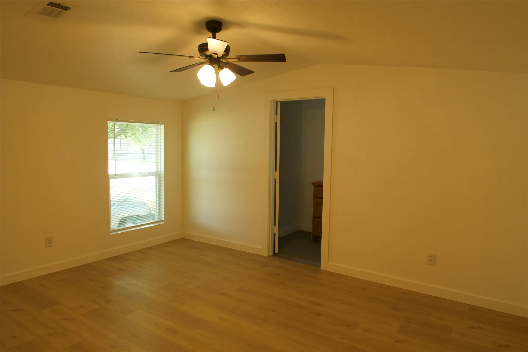 Spare room with a ceiling fan, light wood-style floors, lofted ceiling, and baseboards